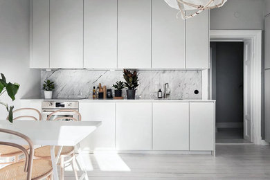 Inspiration pour une cuisine minimaliste avec un placard à porte plane, des portes de placard blanches, plan de travail en marbre, une crédence en marbre et aucun îlot.