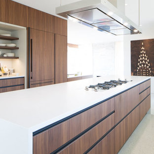Ejemplo de cocina comedor de galera, minimalista, grande, con fregadero bajoencimera, armarios con paneles lisos, puertas de armario de madera oscura, encimera de cuarzo compacto, salpicadero blanco, salpicadero de losas de piedra, electrodomésticos negros, suelo de terrazo, una isla y encimeras blancas