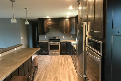 Inspiration for a mid-sized timeless l-shaped light wood floor open concept kitchen remodel in Milwaukee with dark wood cabinets, concrete countertops, stainless steel appliances and no island