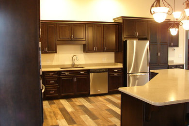 Eat-in kitchen - mid-sized traditional l-shaped medium tone wood floor eat-in kitchen idea in Charlotte with a drop-in sink, recessed-panel cabinets, dark wood cabinets, granite countertops, stainless steel appliances and an island