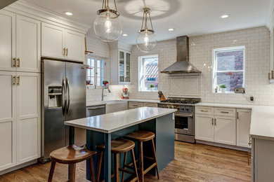 Example of a transitional u-shaped medium tone wood floor kitchen design in St Louis with shaker cabinets, white cabinets, granite countertops, white backsplash, subway tile backsplash, stainless steel appliances and an island