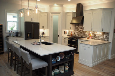 Example of a mid-sized kitchen design in Tampa with recessed-panel cabinets, white cabinets and an island