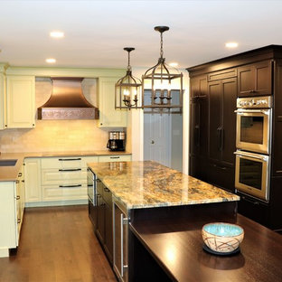 Photo of a large mediterranean eat-in kitchen in Detroit with a single-bowl sink, granite benchtops, stainless steel appliances, with island, recessed-panel cabinets, green cabinets, yellow splashback, marble splashback, dark hardwood floors, brown floor and brown benchtop.