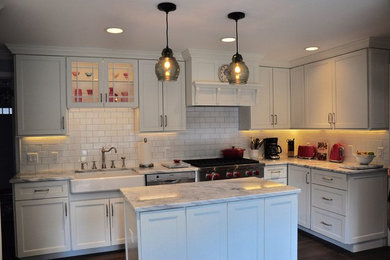 Moderne Küche in L-Form mit Landhausspüle, Schrankfronten im Shaker-Stil, weißen Schränken, Granit-Arbeitsplatte, Küchenrückwand in Weiß, Rückwand aus Metrofliesen, dunklem Holzboden und Kücheninsel in New York