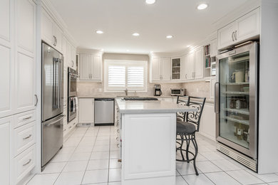 Large u-shaped ceramic tile and white floor kitchen photo in Toronto with beige backsplash, stainless steel appliances and an island