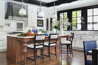 Inspiration for a large transitional l-shaped medium tone wood floor and brown floor eat-in kitchen remodel in New York with beaded inset cabinets, white cabinets, white backsplash, subway tile backsplash, stainless steel appliances, an island, a farmhouse sink and marble countertops