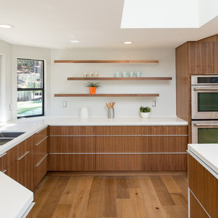 Example of a large minimalist u-shaped medium tone wood floor open concept kitchen design in San Diego with an undermount sink, flat-panel cabinets, dark wood cabinets, quartz countertops, white backsplash, stainless steel appliances and an island