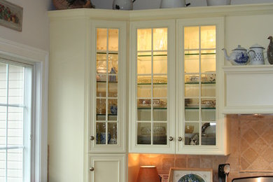 Modelo de cocinas en L campestre abierta con fregadero bajoencimera, armarios tipo vitrina, puertas de armario amarillas, encimera de granito, salpicadero beige y salpicadero de azulejos de cerámica