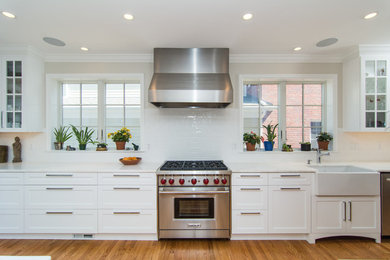 Mid-sized trendy galley medium tone wood floor open concept kitchen photo in DC Metro with a farmhouse sink, white cabinets, marble countertops, white backsplash, porcelain backsplash, stainless steel appliances and an island
