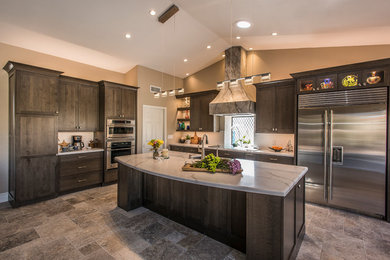 Design ideas for a large traditional l-shaped open plan kitchen in Phoenix with a belfast sink, shaker cabinets, dark wood cabinets, engineered stone countertops, white splashback, porcelain splashback, stainless steel appliances, travertine flooring, an island, beige floors and white worktops.