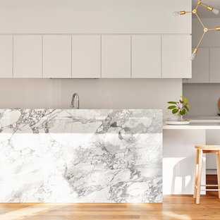 Inspiration for a contemporary l-shaped kitchen in Geelong with white cabinets, marble benchtops, with island, flat-panel cabinets, stainless steel appliances, medium hardwood floors, brown floor and white benchtop.