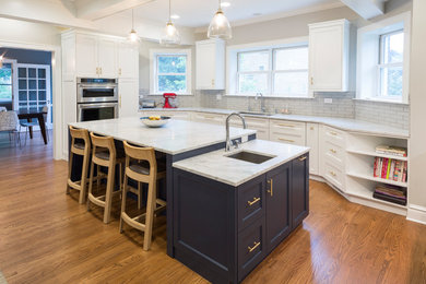 Bild på ett stort vintage vit vitt kök, med en undermonterad diskho, skåp i shakerstil, blå skåp, marmorbänkskiva, grått stänkskydd, stänkskydd i tunnelbanekakel, rostfria vitvaror, mellanmörkt trägolv, en köksö och brunt golv