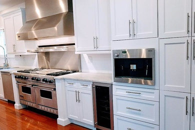 Inspiration for a contemporary l-shaped medium tone wood floor eat-in kitchen remodel in Chicago with a double-bowl sink, recessed-panel cabinets, white cabinets, marble countertops, white backsplash, subway tile backsplash, stainless steel appliances and an island