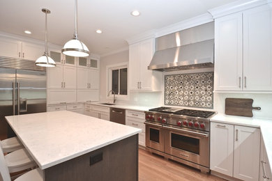 Transitional medium tone wood floor kitchen photo in Chicago with an undermount sink, recessed-panel cabinets, white cabinets, quartz countertops, stainless steel appliances and an island