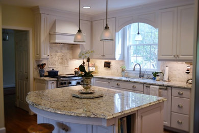 Example of a classic l-shaped medium tone wood floor kitchen design in Richmond with an undermount sink, raised-panel cabinets, white cabinets, granite countertops, paneled appliances, an island, stone tile backsplash and beige backsplash
