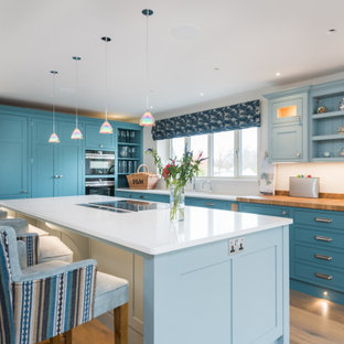 Photo of a large classic l-shaped kitchen in Other with shaker cabinets, blue cabinets, wood worktops, white splashback, medium hardwood flooring, an island, beige floors and beige worktops.