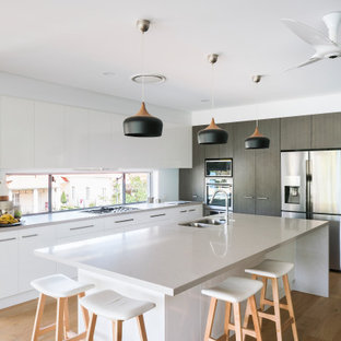 Design ideas for a mid-sized contemporary l-shaped open plan kitchen in Brisbane with an undermount sink, flat-panel cabinets, white cabinets, quartz benchtops, stainless steel appliances, with island, white benchtop, window splashback, medium hardwood floors and brown floor.