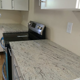 Example of a trendy u-shaped kitchen design in Miami with white cabinets, granite countertops, stainless steel appliances and a double-bowl sink