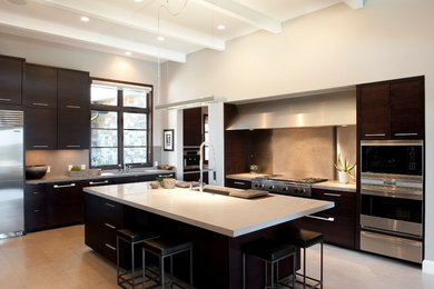 Photo of a large contemporary l-shaped kitchen/diner in Austin with a submerged sink, flat-panel cabinets, dark wood cabinets, marble worktops, beige splashback, stone slab splashback, stainless steel appliances, travertine flooring, an island and beige floors.
