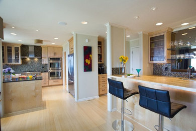 Foto de cocina minimalista con puertas de armario de madera clara, encimera de cuarcita, salpicadero con mosaicos de azulejos, electrodomésticos de acero inoxidable y suelo de bambú