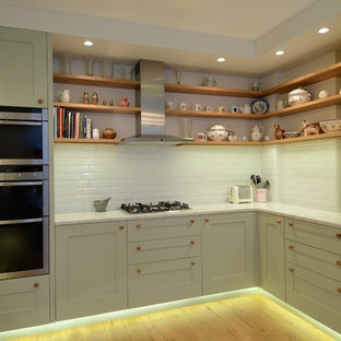Small scandinavian u-shaped separate kitchen in London with an integrated sink, shaker cabinets, green cabinets, marble benchtops, white splashback, subway tile splashback, stainless steel appliances, light hardwood floors and no island.
