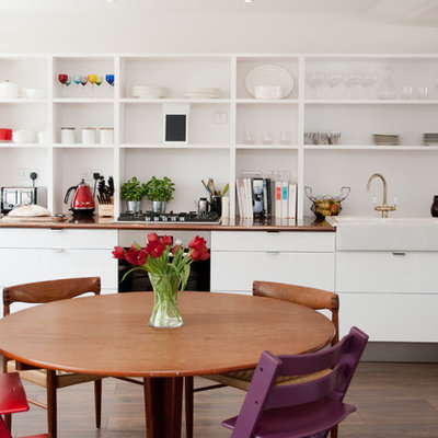 Trendy galley medium tone wood floor eat-in kitchen photo in London with a farmhouse sink, open cabinets and white cabinets