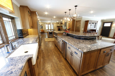 Eat-in kitchen - mid-sized craftsman galley dark wood floor eat-in kitchen idea in Other with a farmhouse sink, recessed-panel cabinets, dark wood cabinets, an island, granite countertops, black backsplash, ceramic backsplash and stainless steel appliances