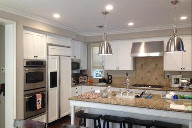 Eat-in kitchen - traditional l-shaped dark wood floor eat-in kitchen idea in Orange County with an undermount sink, shaker cabinets, white cabinets, granite countertops, beige backsplash, stone tile backsplash, white appliances and an island