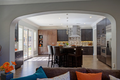 Mid-sized trendy u-shaped light wood floor and beige floor eat-in kitchen photo in Portland with a double-bowl sink, flat-panel cabinets, black cabinets, marble countertops, stainless steel appliances and an island