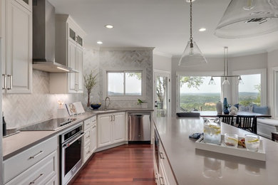 Large transitional l-shaped medium tone wood floor open concept kitchen photo in Austin with an undermount sink, raised-panel cabinets, white cabinets, quartz countertops, marble backsplash, an island, gray countertops, gray backsplash and stainless steel appliances