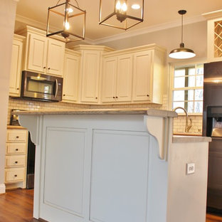 Photo of a mid-sized arts and crafts l-shaped eat-in kitchen in Birmingham with a double-bowl sink, raised-panel cabinets, white cabinets, limestone benchtops, white splashback, subway tile splashback, white appliances, laminate floors, with island and brown floor.