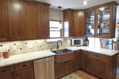 Example of a small country l-shaped light wood floor and yellow floor eat-in kitchen design in Other with a farmhouse sink, shaker cabinets, brown cabinets, granite countertops, beige backsplash, ceramic backsplash, stainless steel appliances and a peninsula