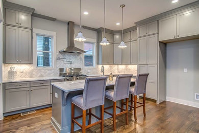 Mid-sized transitional l-shaped dark wood floor eat-in kitchen photo in Raleigh with an undermount sink, shaker cabinets, gray cabinets, quartz countertops, gray backsplash, stone tile backsplash, paneled appliances and an island