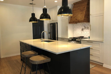 Example of a large transitional single-wall light wood floor and brown floor enclosed kitchen design in Austin with an undermount sink, shaker cabinets, white cabinets, marble countertops, white backsplash, subway tile backsplash, stainless steel appliances, an island and white countertops