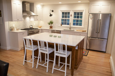 Inspiration for a mid-sized transitional l-shaped light wood floor open concept kitchen remodel in Philadelphia with an undermount sink, recessed-panel cabinets, white cabinets, quartz countertops, gray backsplash, stainless steel appliances and an island