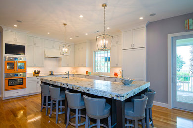 Eat-in kitchen - large modern l-shaped medium tone wood floor and brown floor eat-in kitchen idea in Charleston with a farmhouse sink, shaker cabinets, white cabinets, granite countertops, white backsplash, ceramic backsplash, colored appliances and an island
