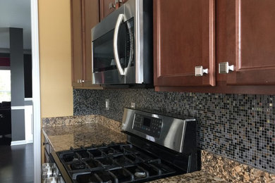 Mid-sized elegant u-shaped dark wood floor and brown floor eat-in kitchen photo in Atlanta with an undermount sink, shaker cabinets, dark wood cabinets, granite countertops, black backsplash, mosaic tile backsplash, stainless steel appliances and an island