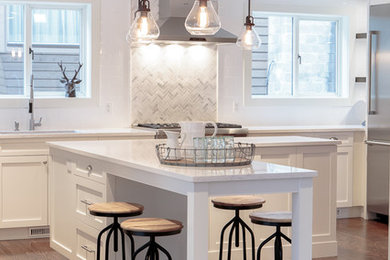 Eat-in kitchen - mid-sized transitional l-shaped medium tone wood floor eat-in kitchen idea in Vancouver with an undermount sink, shaker cabinets, white cabinets, quartz countertops, gray backsplash, stone tile backsplash, stainless steel appliances and an island