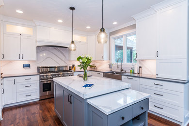 Eat-in kitchen - large transitional u-shaped dark wood floor and brown floor eat-in kitchen idea in Other with a farmhouse sink, recessed-panel cabinets, white cabinets, marble countertops, white backsplash, stone slab backsplash, paneled appliances and an island