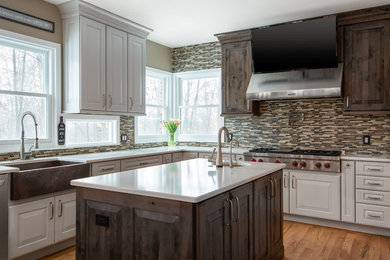 Transitional light wood floor kitchen photo in Detroit with a farmhouse sink, raised-panel cabinets, mosaic tile backsplash, stainless steel appliances and two islands