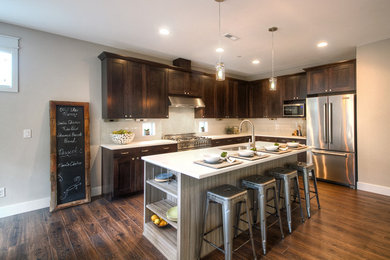 Enclosed kitchen - large transitional l-shaped laminate floor enclosed kitchen idea in Seattle with an undermount sink, shaker cabinets, dark wood cabinets, solid surface countertops, white backsplash, ceramic backsplash, stainless steel appliances and an island