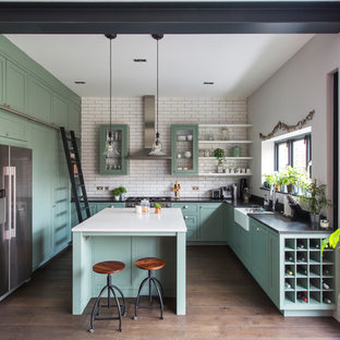 Foto di una cucina contemporanea di medie dimensioni con ante con riquadro incassato, ante verdi, pavimento in legno massello medio, pavimento marrone, lavello stile country, paraspruzzi con piastrelle diamantate, elettrodomestici in acciaio inossidabile, paraspruzzi bianco, top in granito e top nero