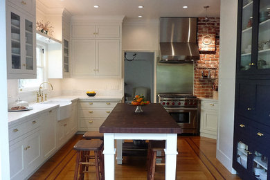 Huge arts and crafts l-shaped medium tone wood floor and brown floor eat-in kitchen photo in San Francisco with a farmhouse sink, shaker cabinets, white cabinets, quartz countertops, white backsplash, stone slab backsplash, stainless steel appliances, an island and white countertops