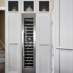 Idée de décoration pour une grand cuisine américaine design en U avec un évier encastré, un placard à porte shaker, des portes de placard blanches, un plan de travail en marbre, une crédence blanche, un électroménager en acier inoxydable, un sol en bois foncé, un îlot central et une crédence en pierre calcaire.