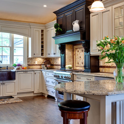 Example of a large classic u-shaped medium tone wood floor and brown floor eat-in kitchen design in Atlanta with raised-panel cabinets, stainless steel appliances, a farmhouse sink, white cabinets, granite countertops, multicolored backsplash, stone tile backsplash, a peninsula and beige countertops