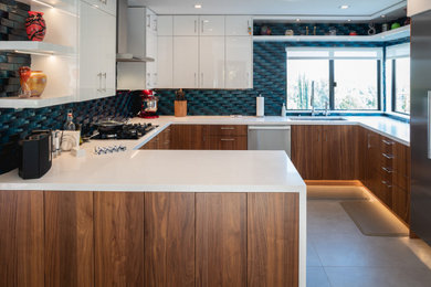 Inspiration for a large modern u-shaped porcelain tile and gray floor eat-in kitchen remodel in Los Angeles with an undermount sink, flat-panel cabinets, medium tone wood cabinets, quartz countertops, blue backsplash, glass tile backsplash, stainless steel appliances, a peninsula and white countertops