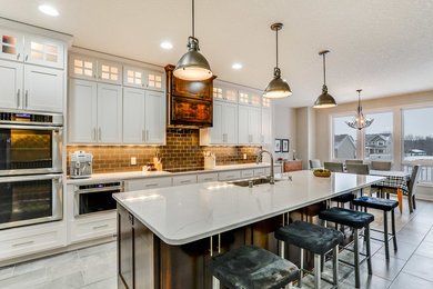 Eclectic galley porcelain tile open concept kitchen photo in Minneapolis with a farmhouse sink, shaker cabinets, solid surface countertops, gray backsplash, subway tile backsplash, stainless steel appliances and an island