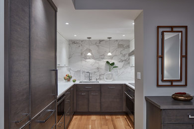 Enclosed kitchen - small modern u-shaped light wood floor and brown floor enclosed kitchen idea in Boston with flat-panel cabinets, dark wood cabinets, no island, an undermount sink, solid surface countertops, white backsplash, marble backsplash, stainless steel appliances and white countertops