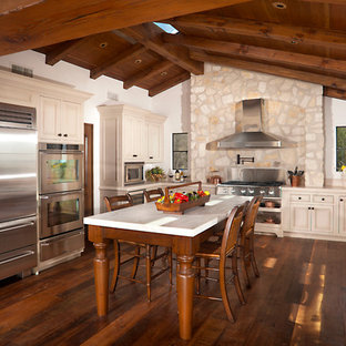 Large mediterranean u-shaped eat-in kitchen in Los Angeles with a farmhouse sink, limestone benchtops, stainless steel appliances, dark hardwood floors and with island.