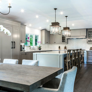 Example of a large classic l-shaped dark wood floor and brown floor eat-in kitchen design in Los Angeles with an undermount sink, white backsplash, paneled appliances, an island, recessed-panel cabinets, gray cabinets, quartz countertops and subway tile backsplash